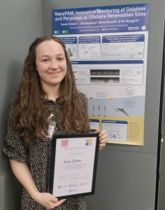 Aura CDT student Sarah Dickson stands in front of her academic poster, holding her award certificate